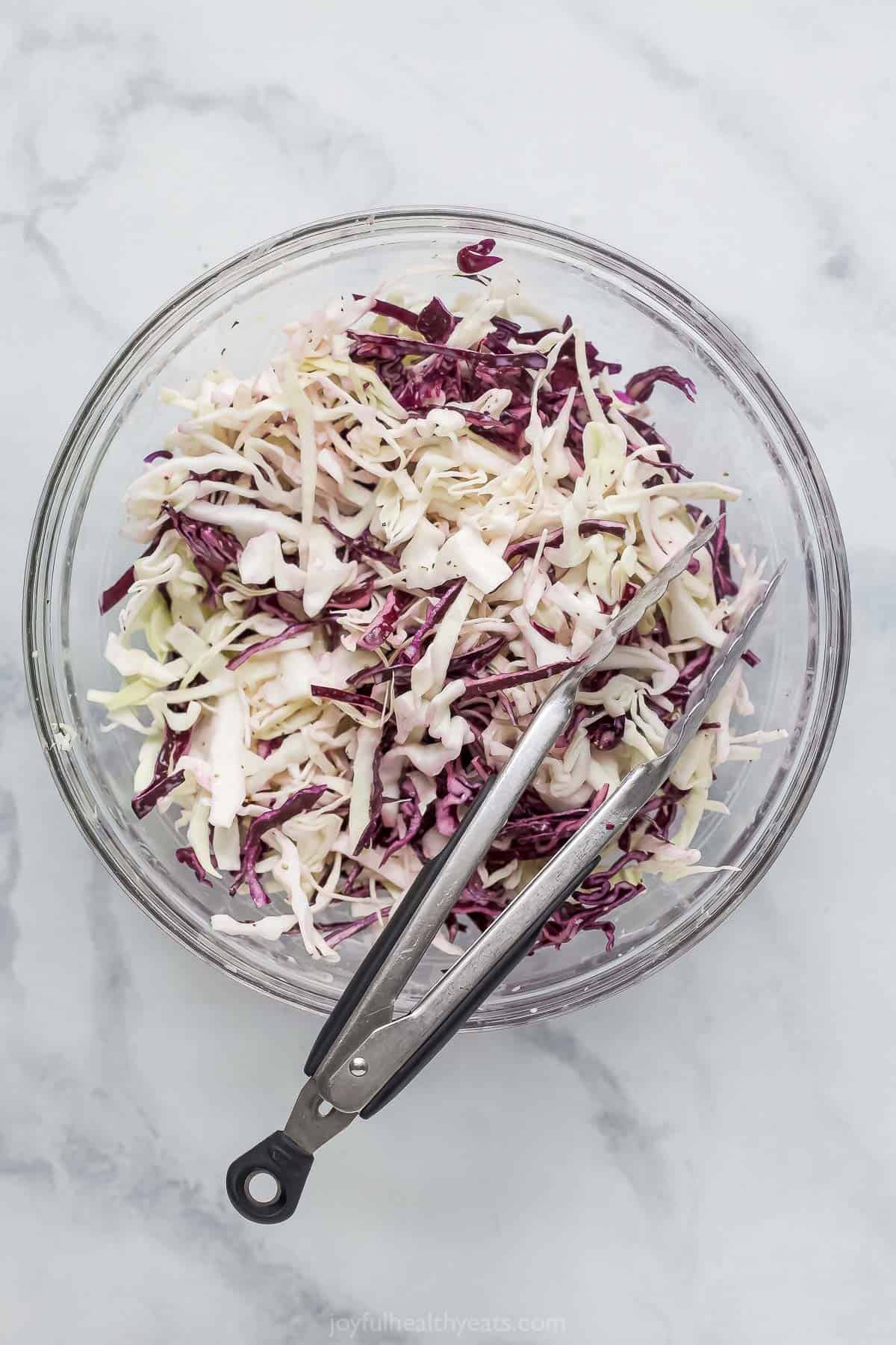 Overhead view of coleslaw in bowl with tongs