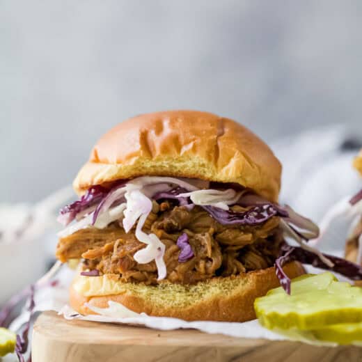 Pulled pork sandwich on wooden board with pickles