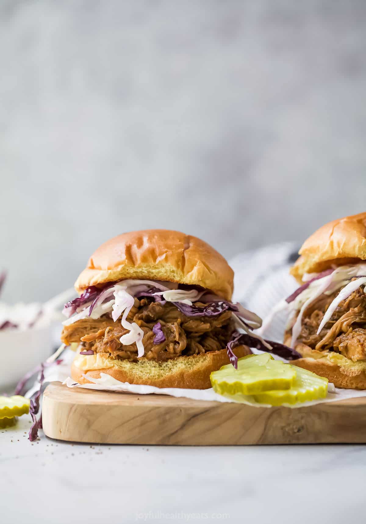 Pulled pork sandwiches on wooden board with pickles