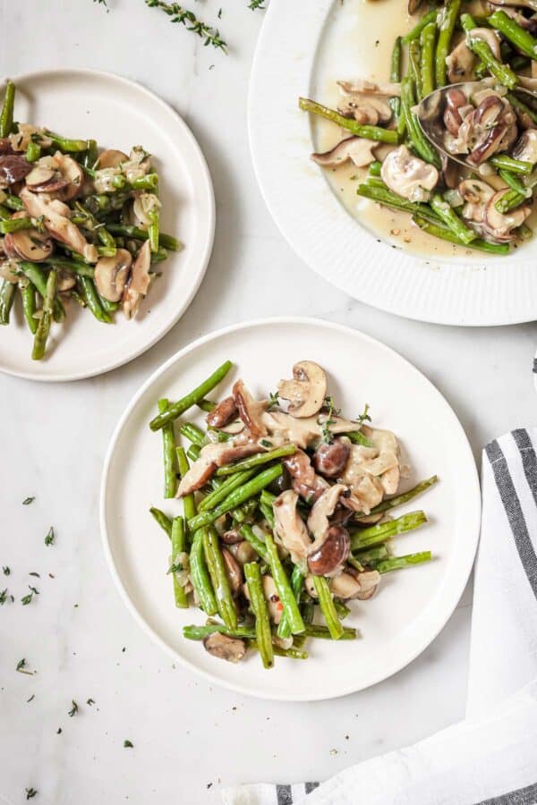 Serving plates with roasted green beans and creamy sauce.