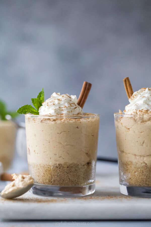 A glass of No Bake Pumpkin Cheesecake with Cool Whip and cinnamon on top.