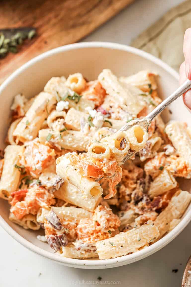 A bowl of creamy rigatoni with goat cheese, butternut squash, bacon, pecans, and roasted red onions.