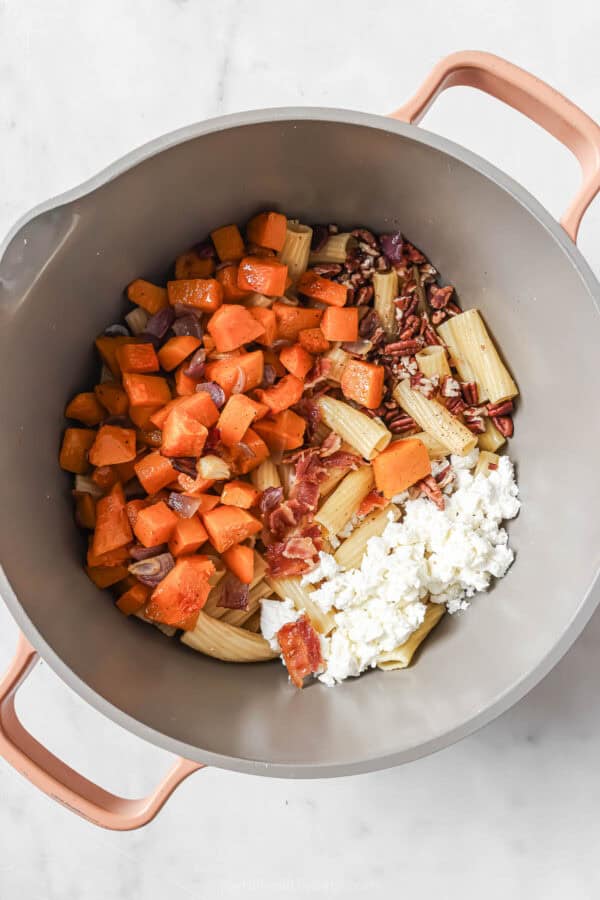 Adding the roasted veggies, goat cheese, bacon, sage, and pecans to the pasta pot. 