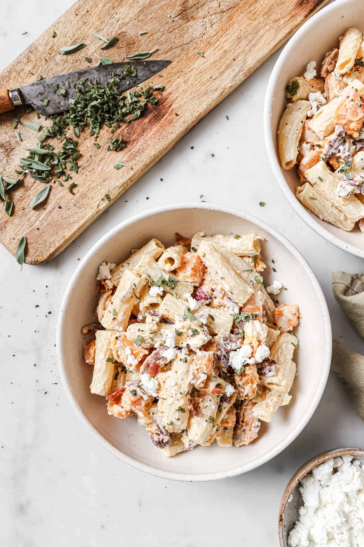 Overhead photo of a bowl of pasta with chopped sage on the side. 