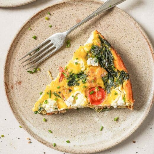 Overhead view of cheesy bacon spinach frittata on plate with fork