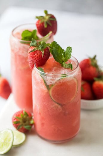 Strawberry limeade in a glass with mint and strawberry garnishes.