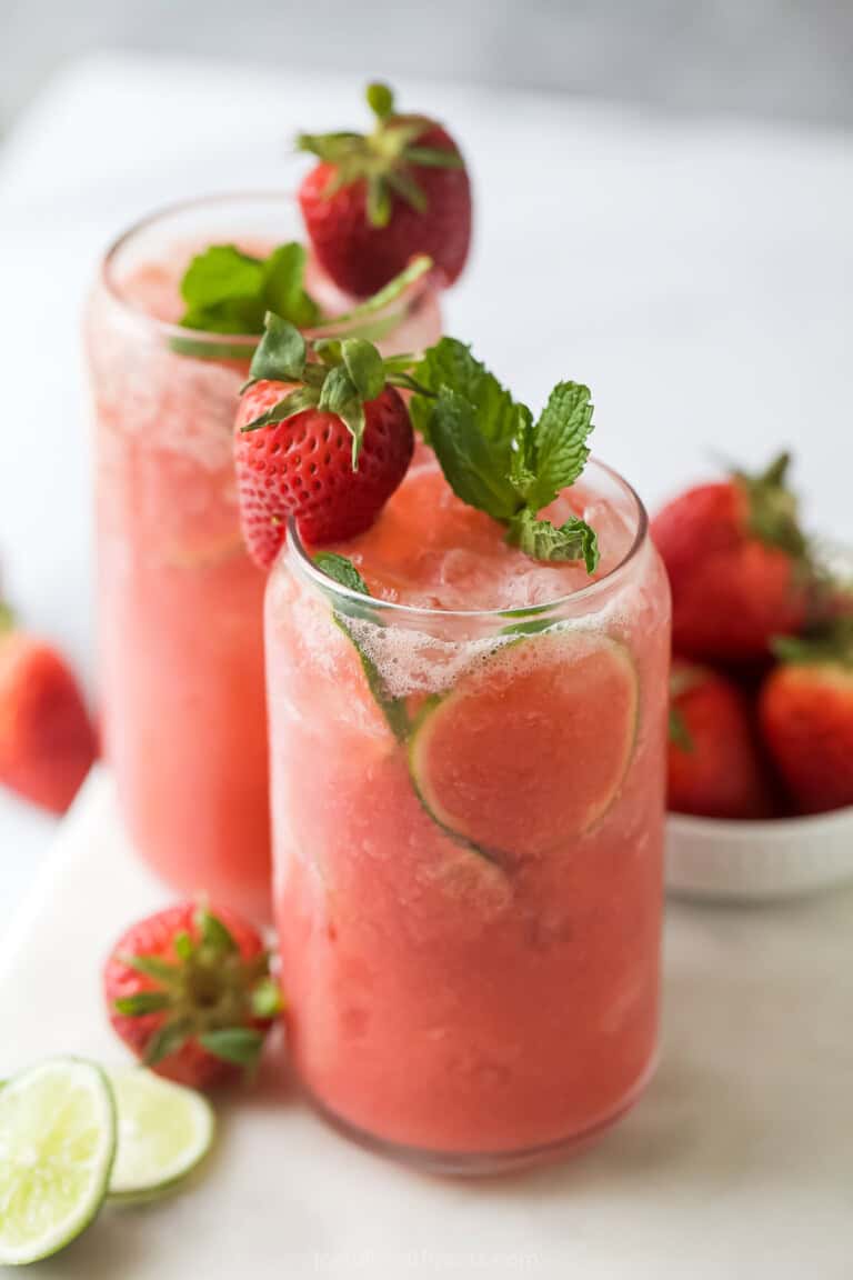 Strawberry limeade in a glass with mint and strawberry garnishes.