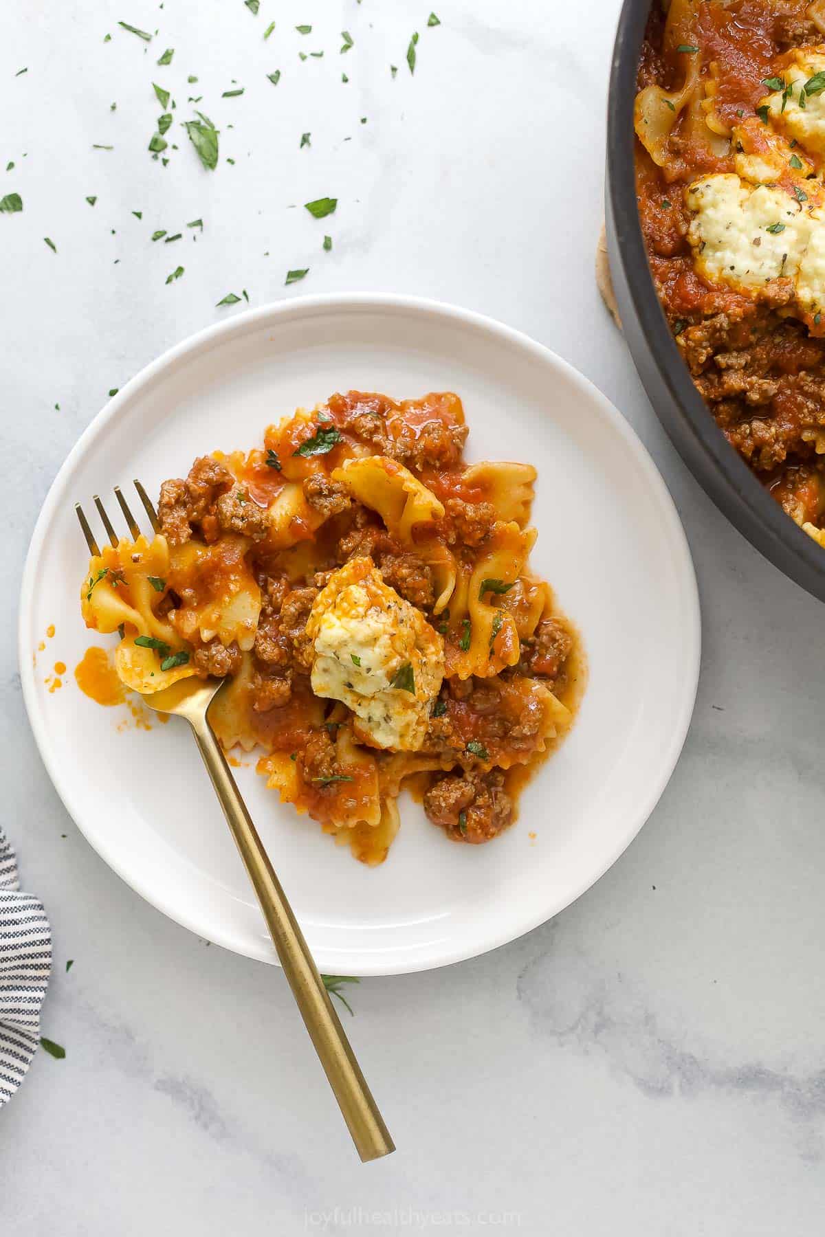 Serving plate of warm skillet lasagna with creamy parmesan-ricotta on top.