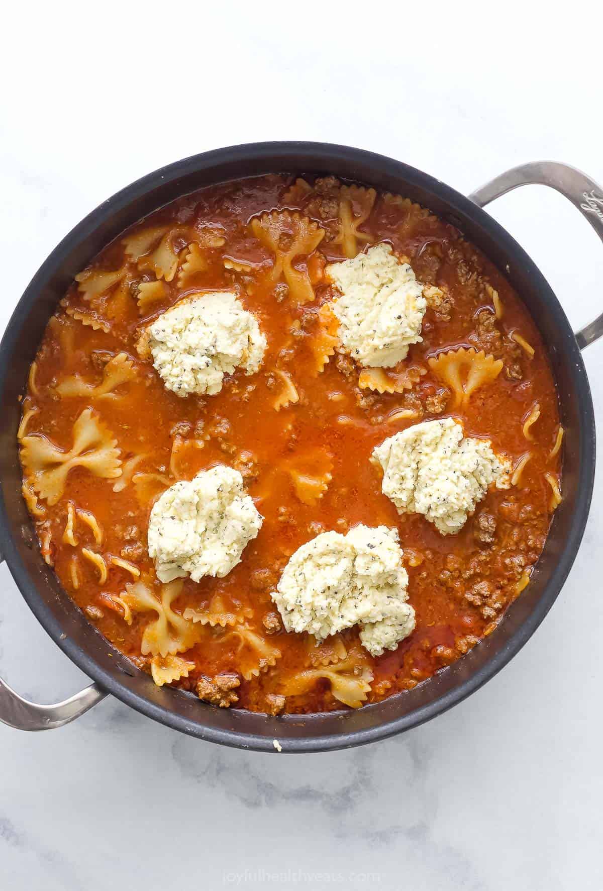 Adding dollops of the ricotta mixture over the pasta. 