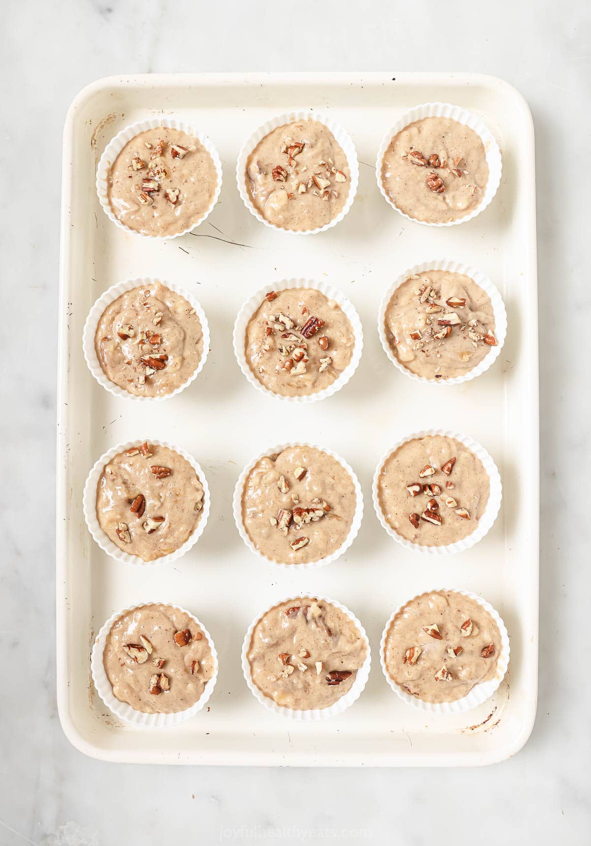 Silicone liners on a baking tray with muffin batter. 