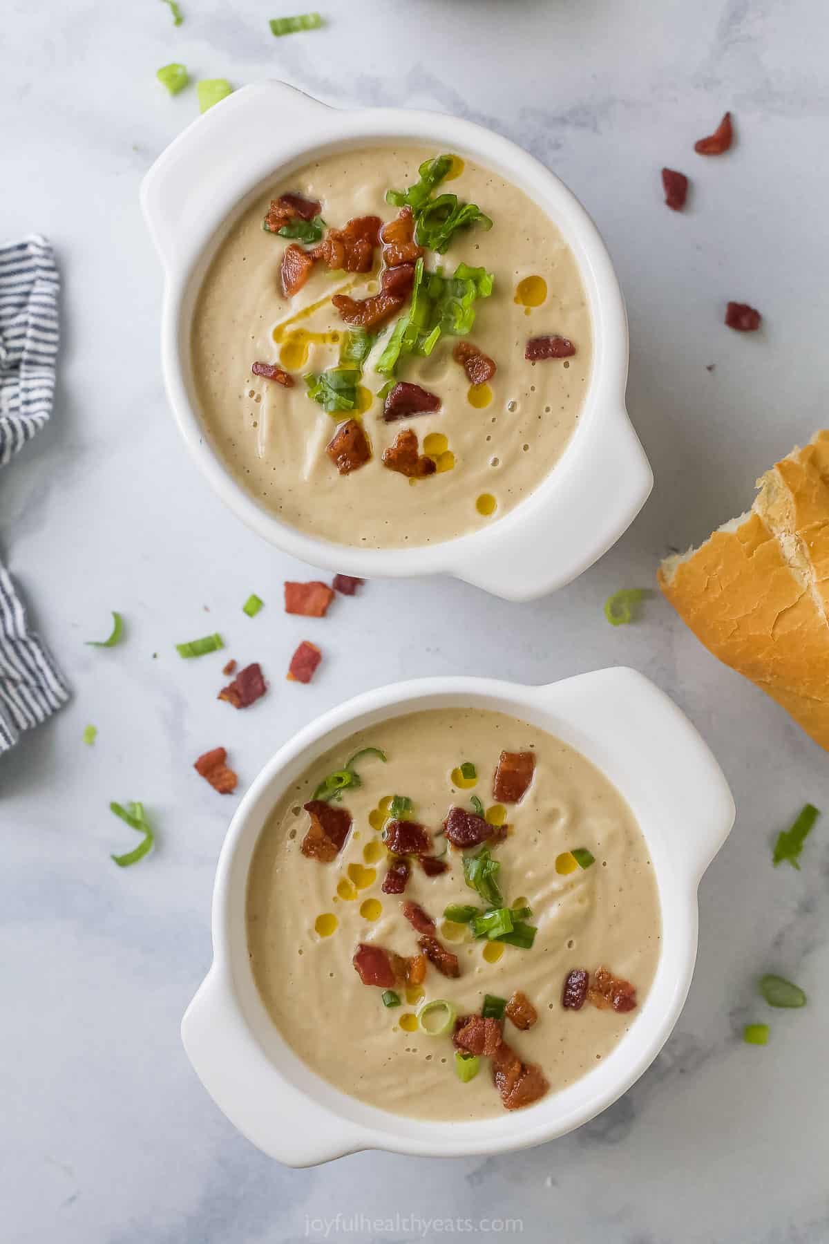 Two bowls of homemade cauliflower soup with bacon, green onions, and chili oil. 