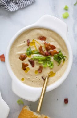 Creamy soup in a bowl with crispy bacon, crunchy green onions, and chili oil.