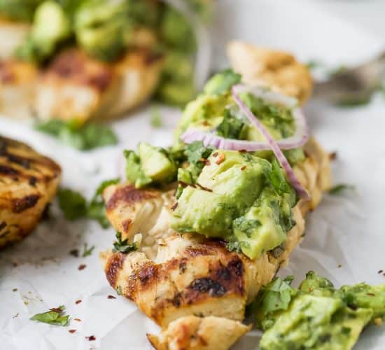 side photo of sliced grilled cilantro lime chicken topped with avocado salsa and red onion