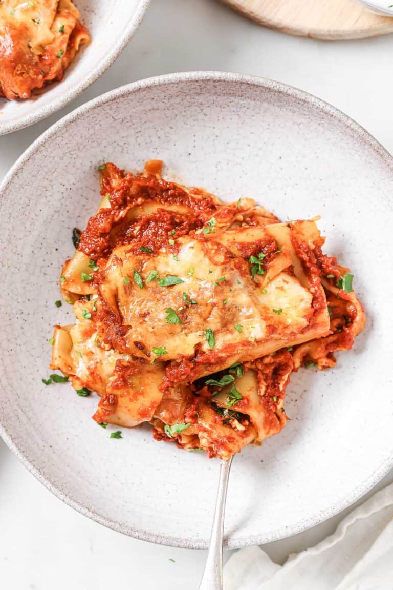 Freshly-made tomatoey lasagna rolls with cottage cheese-spinach filling on a serving plate.