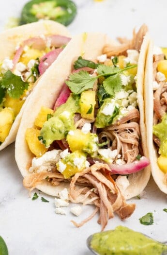 Close-up of pork carnitas tacos with avocado crema.