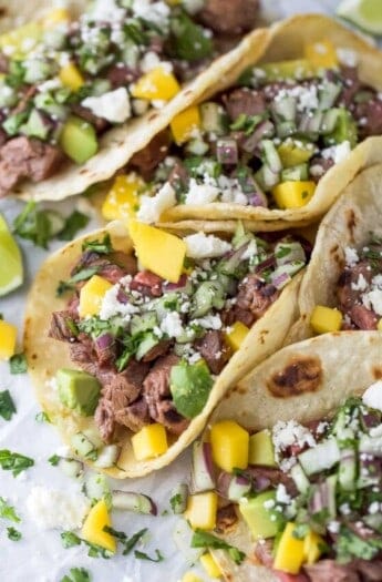 Three street tacos on a parchment-lined tray.