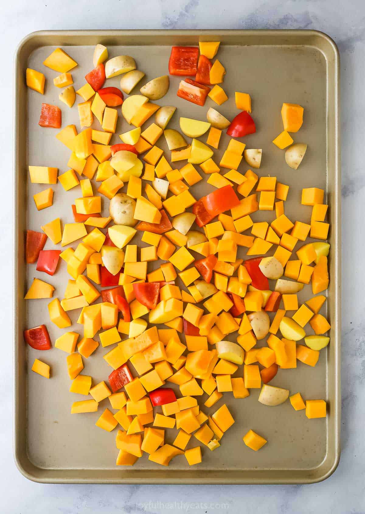 Adding the squash, peppers, and potatoes to the baking tray. 