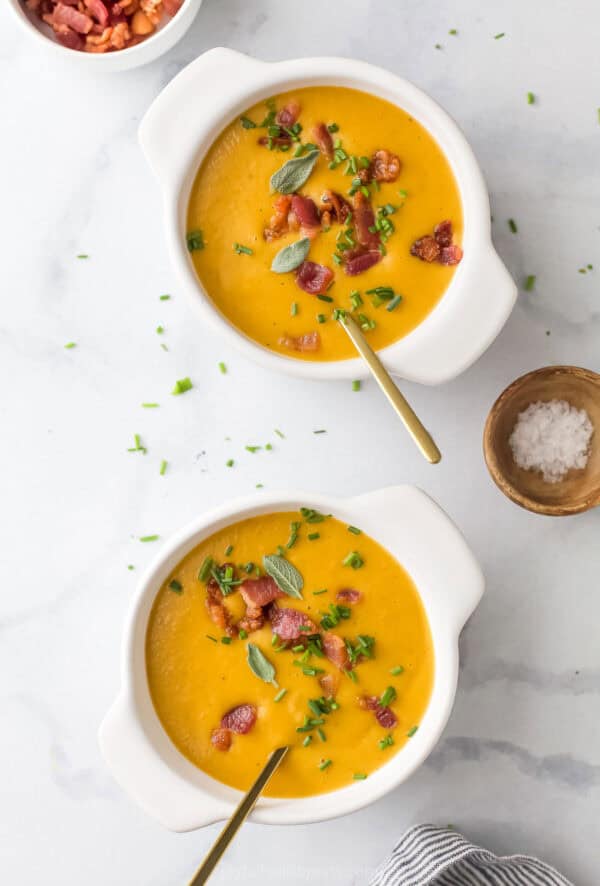 Two bowls of soup with crunchy chives and crispy bacon on top.