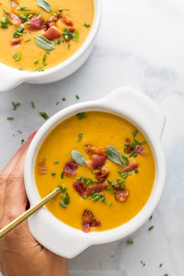 Grabbing a bowl of creamy butternut squash soup with bacon and chives on top.