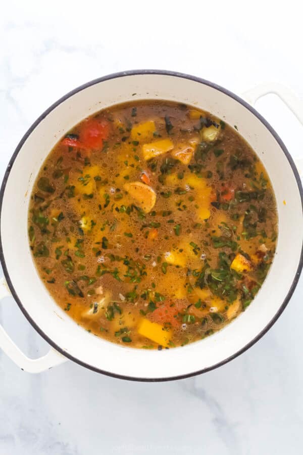 Simmering the veggies, herbs, and spices with the veggie broth. 