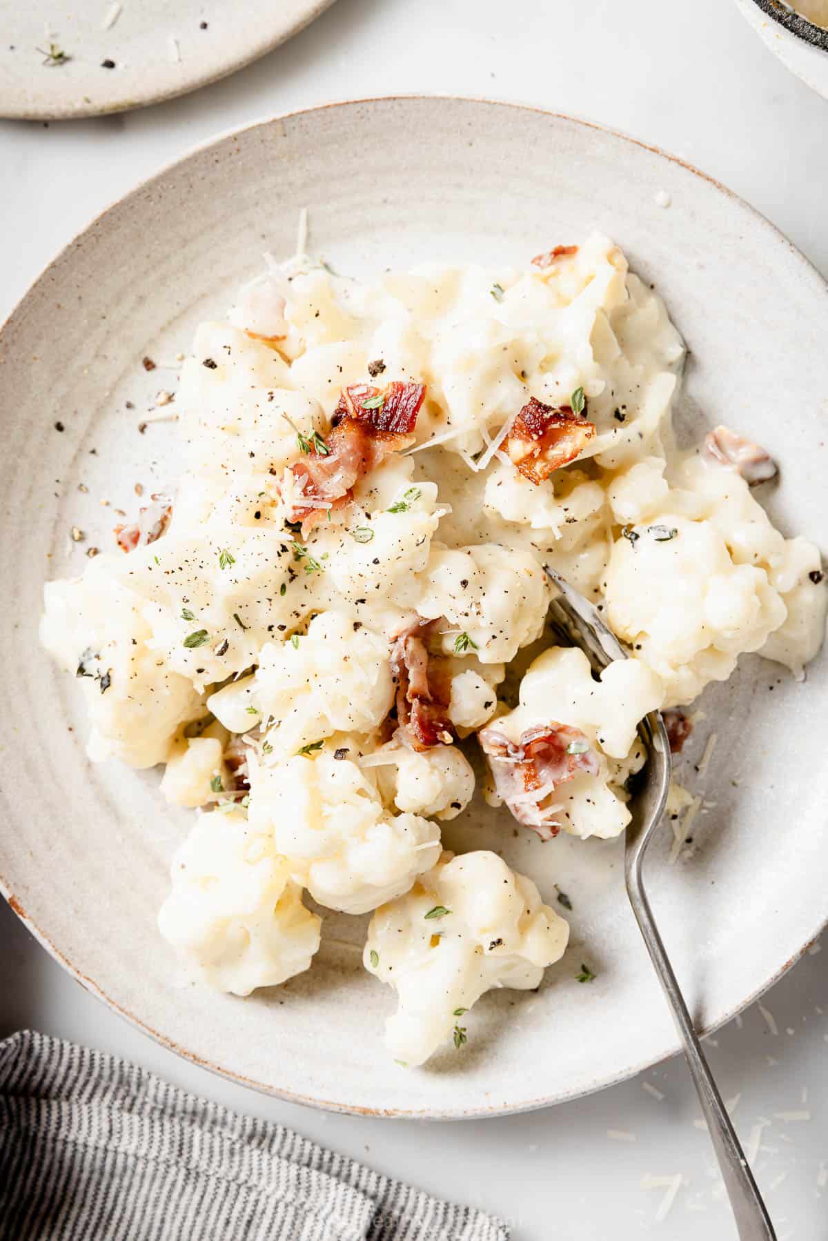 Cauliflower au gratin with crispy bacon in a serving bowl. 