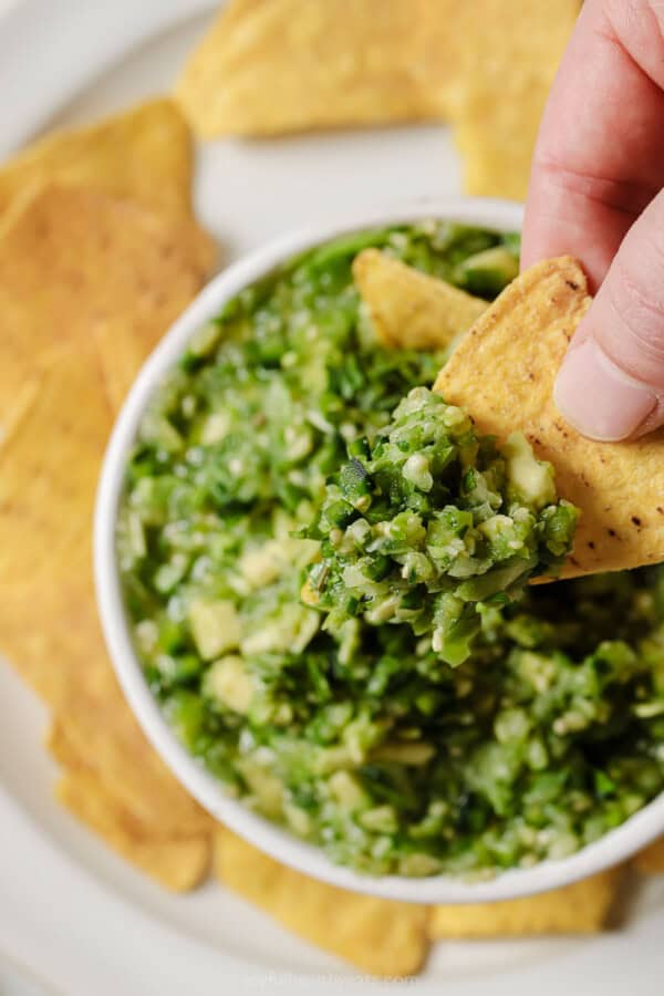 Dip a tortilla chip into chunky avocado salsa verde.