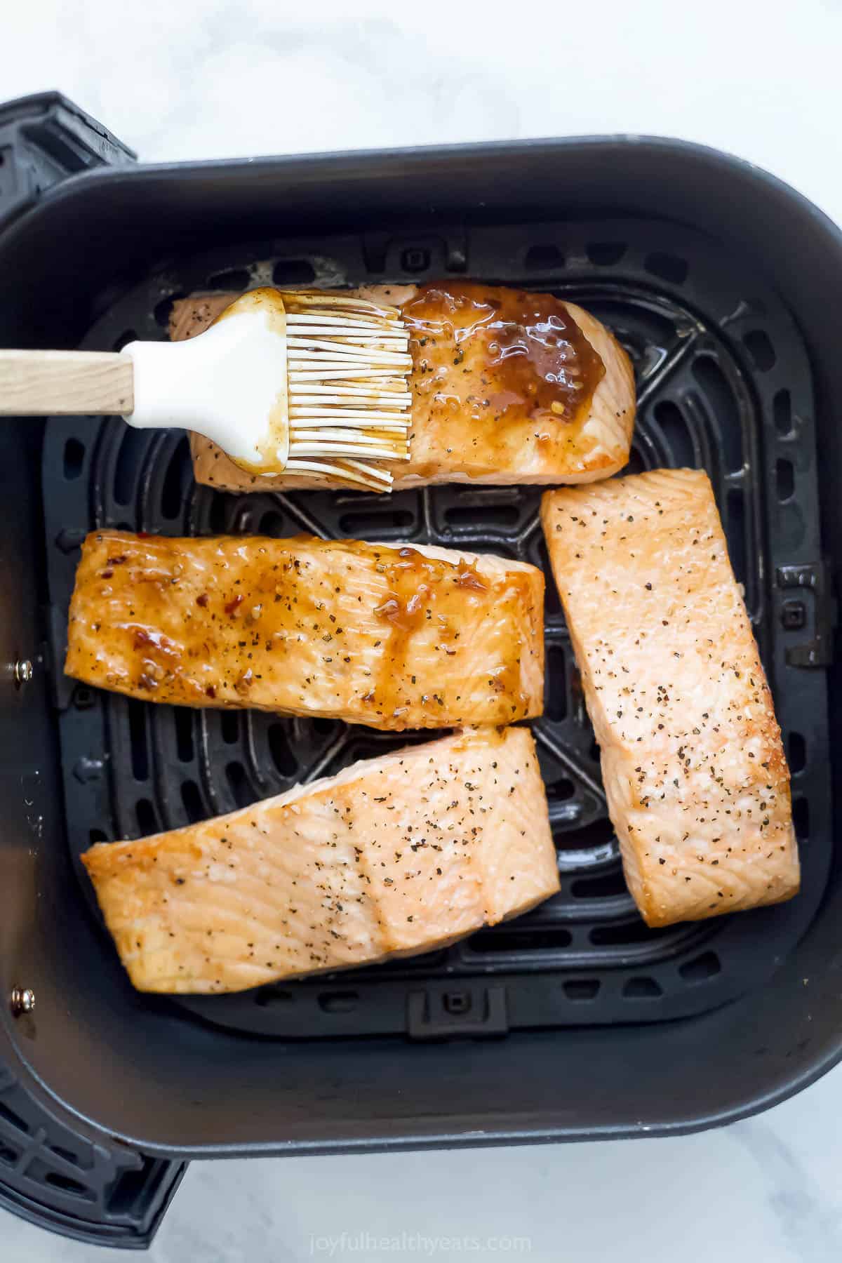 Brushing glaze onto salmon in air fryer