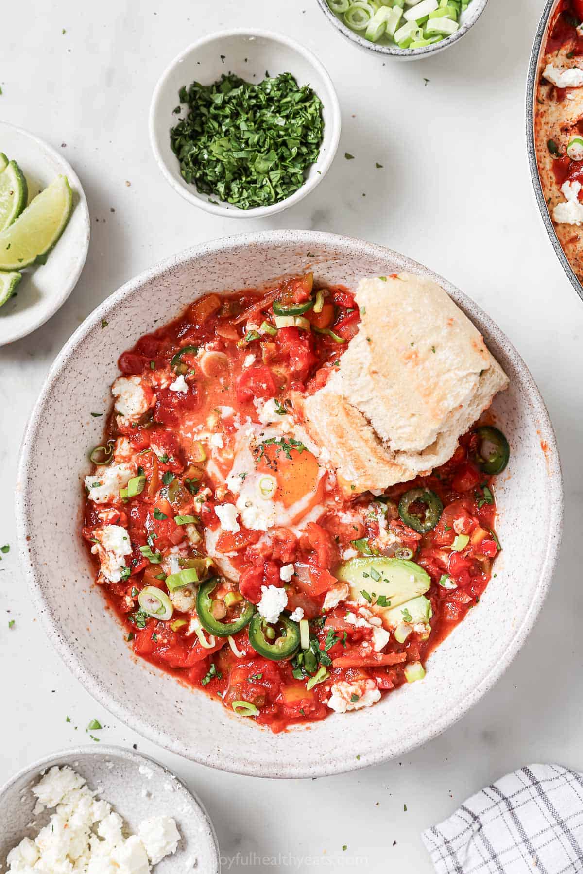 Dipping a piece of baguette into the shakshuka.