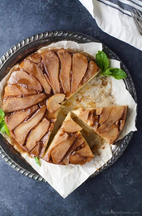 A homemade, sliced pear upside down cake on a serving plate.