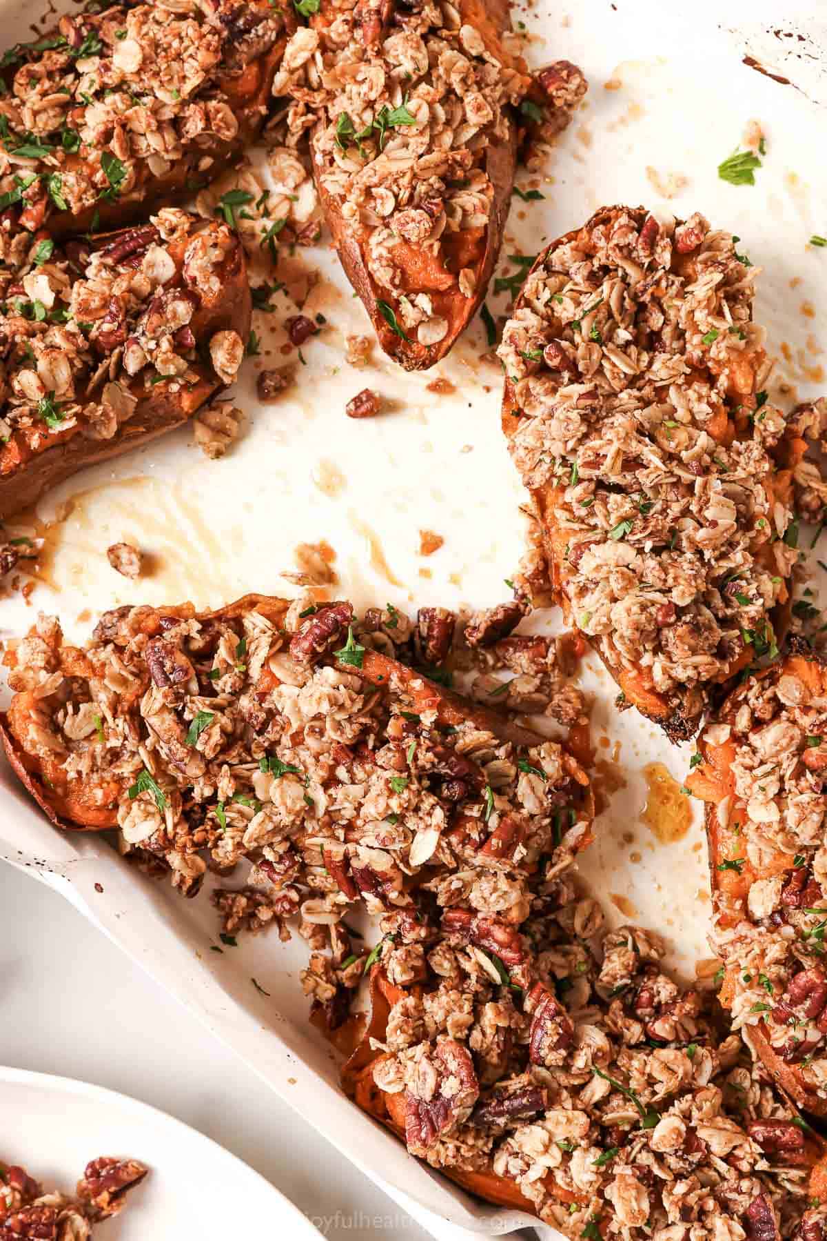 Close-up of twice baked sweet potatoes in the baking sheet with homemade oat-pecan streusel on top.