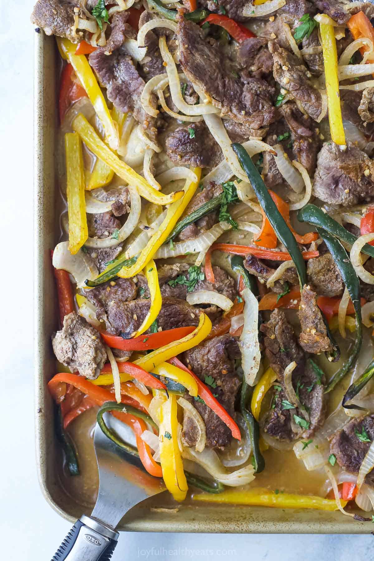 Angled image of juicy, tender beef fajitas with poblanos, peppers and onions.