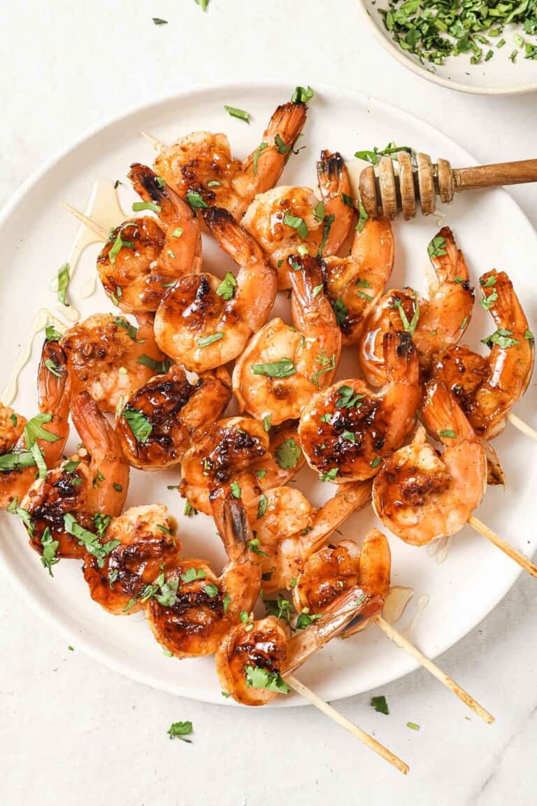 Plate of honey garlic shrimp skewers with cilantro on top.