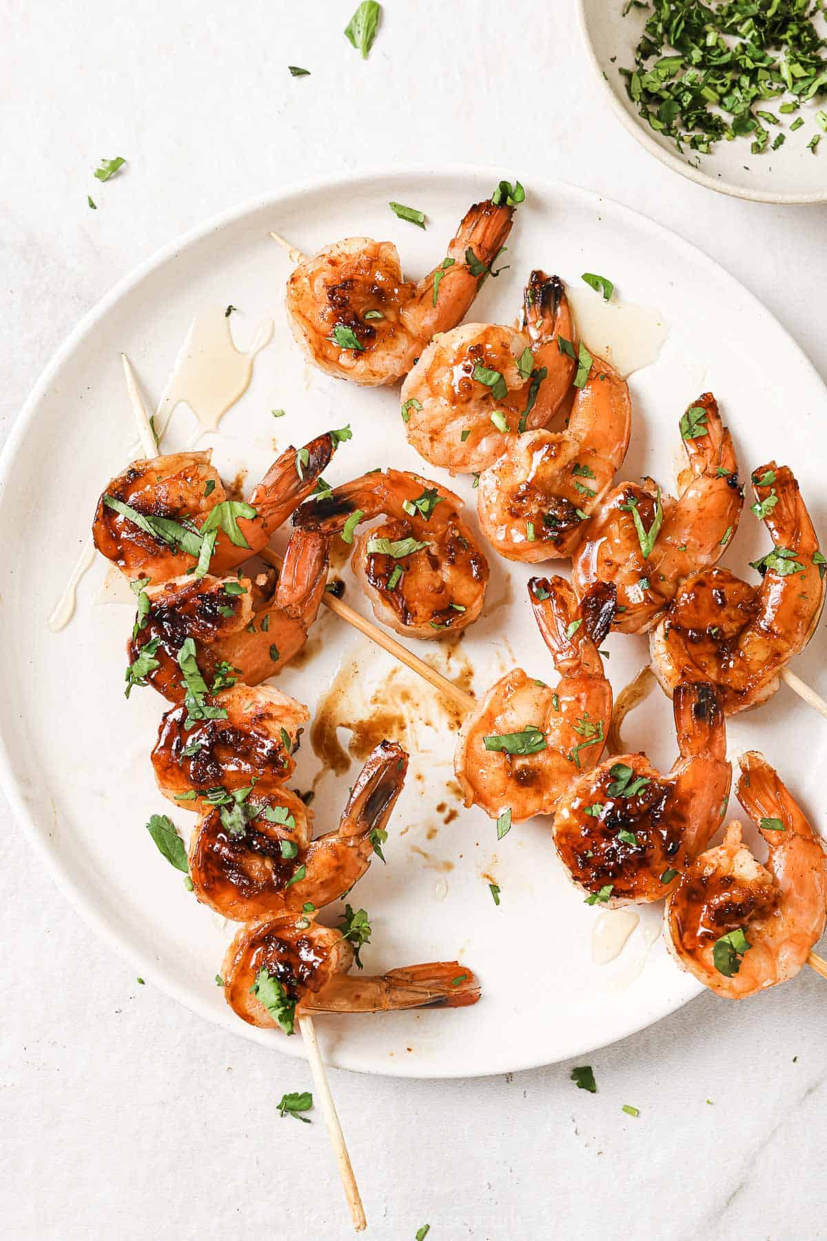 A plate of honey garlic shrimp fresh off the grill with a cilantro garnish. 