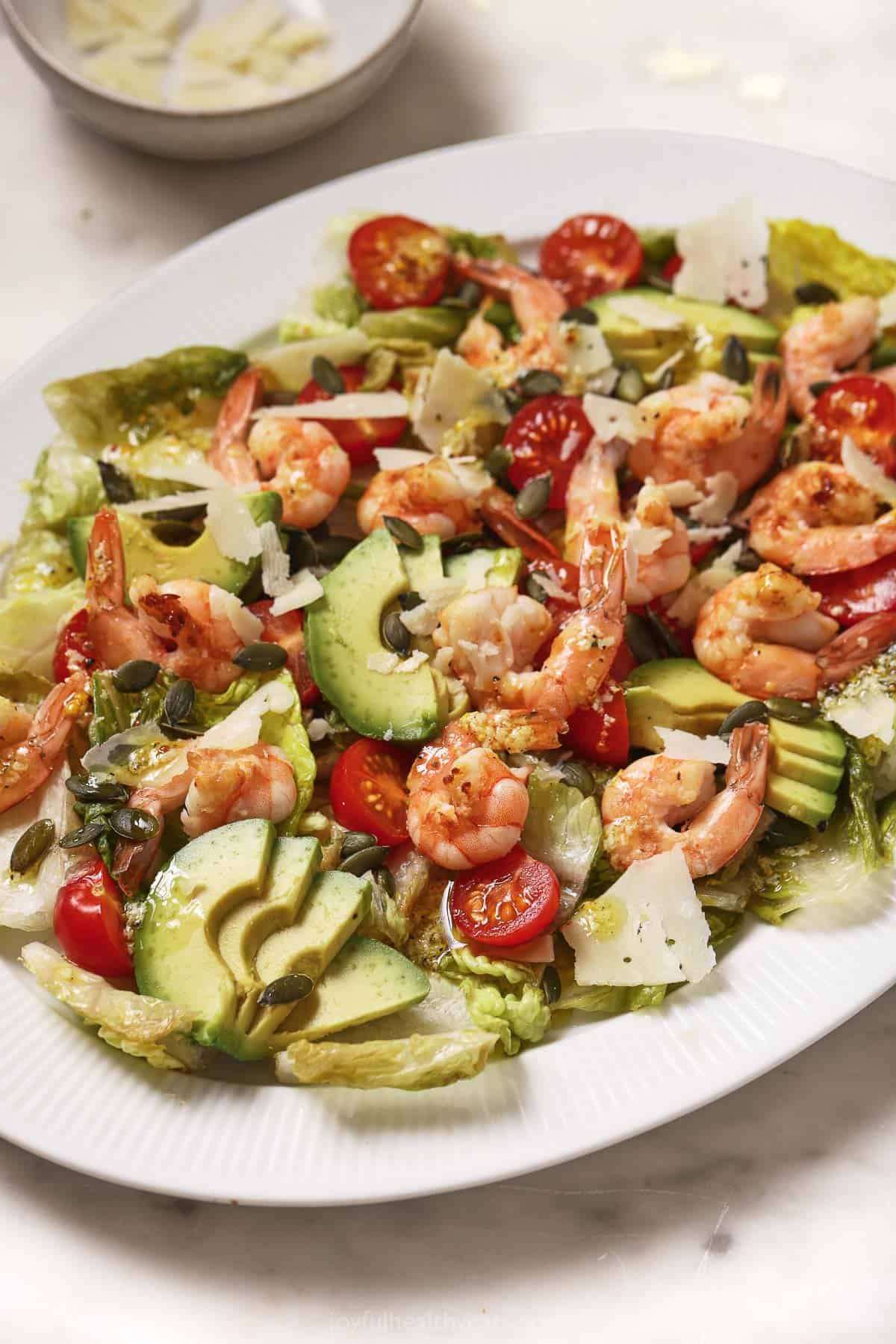 Shrimp caesar salad with grilled lettuce, avocado, tomatoes, and ،memade dressing. 