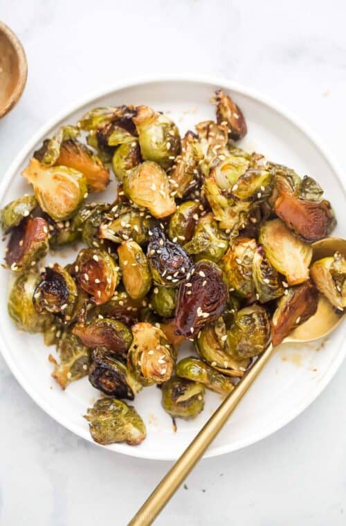 Bowl of homemade honey roasted Brussels sprouts with sesame seeds on top.