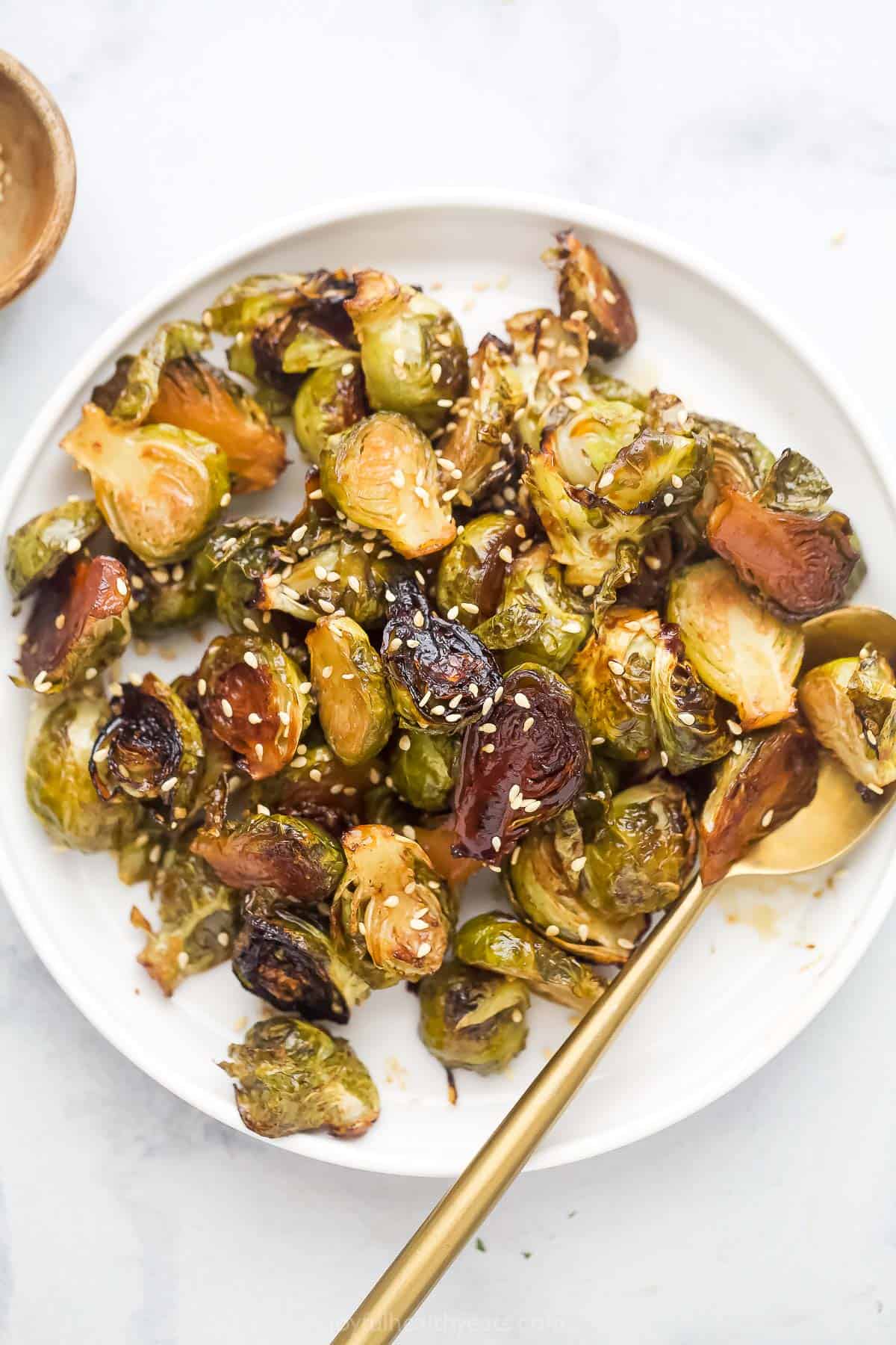 Bowl of homemade honey roasted Brussels sprouts with sesame seeds on top. 