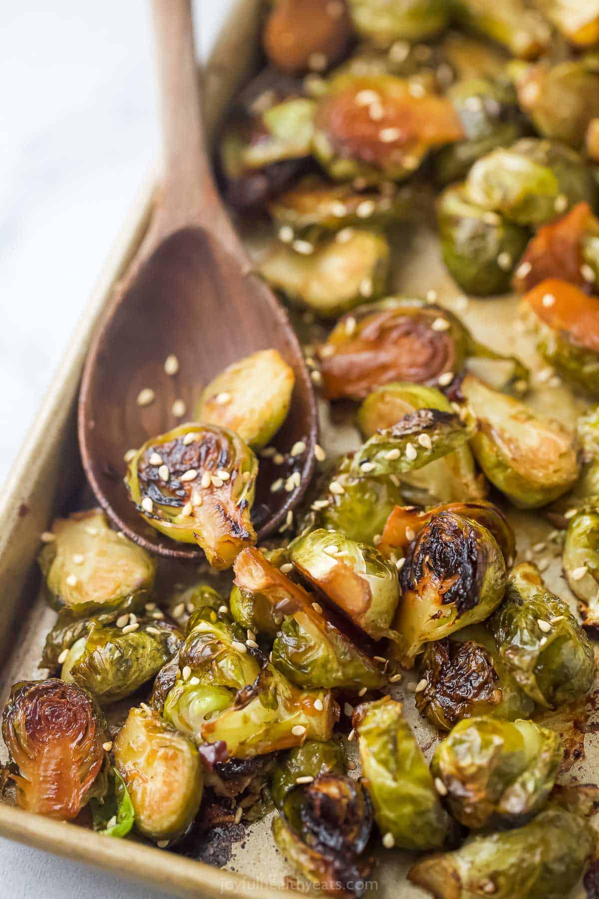 Close-up of the roasted Brussels sprouts with crispy, caramelized edges and a sprinkle of sesame seeds.