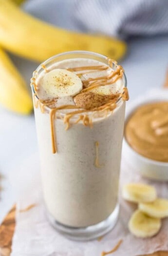 A glass of peanut butter banana smoothie with more peanut butter on top.