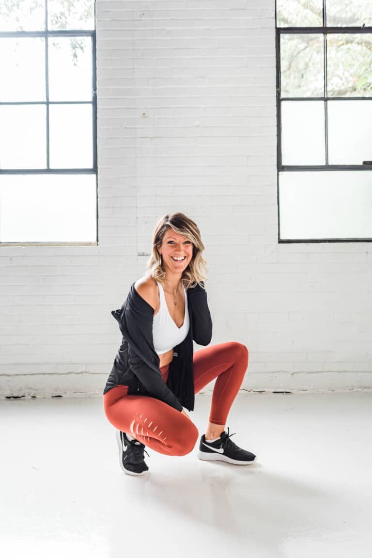 girl in workout clothes squatting and smiling