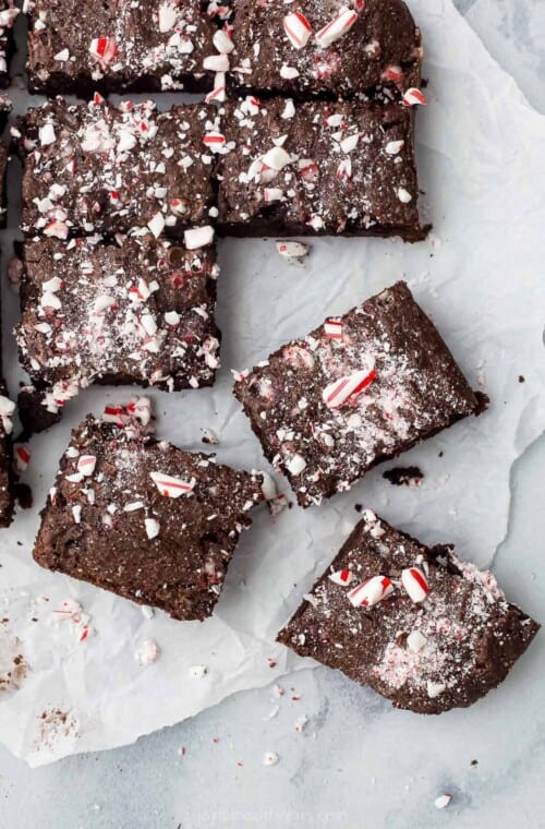 A batch of fudgy brownies on a piece of parchment paper over a marble surface