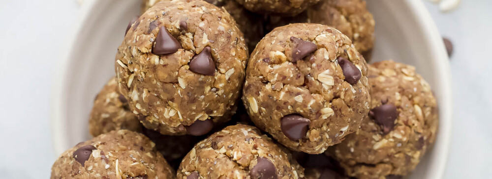 The bird's-eye view of a bowl of protein balls beside a smaller bowl filled with chocolate chips