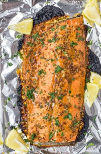 A foil-lined baking sheet with a baked Dijon maple glazed salmon fillet on top of it