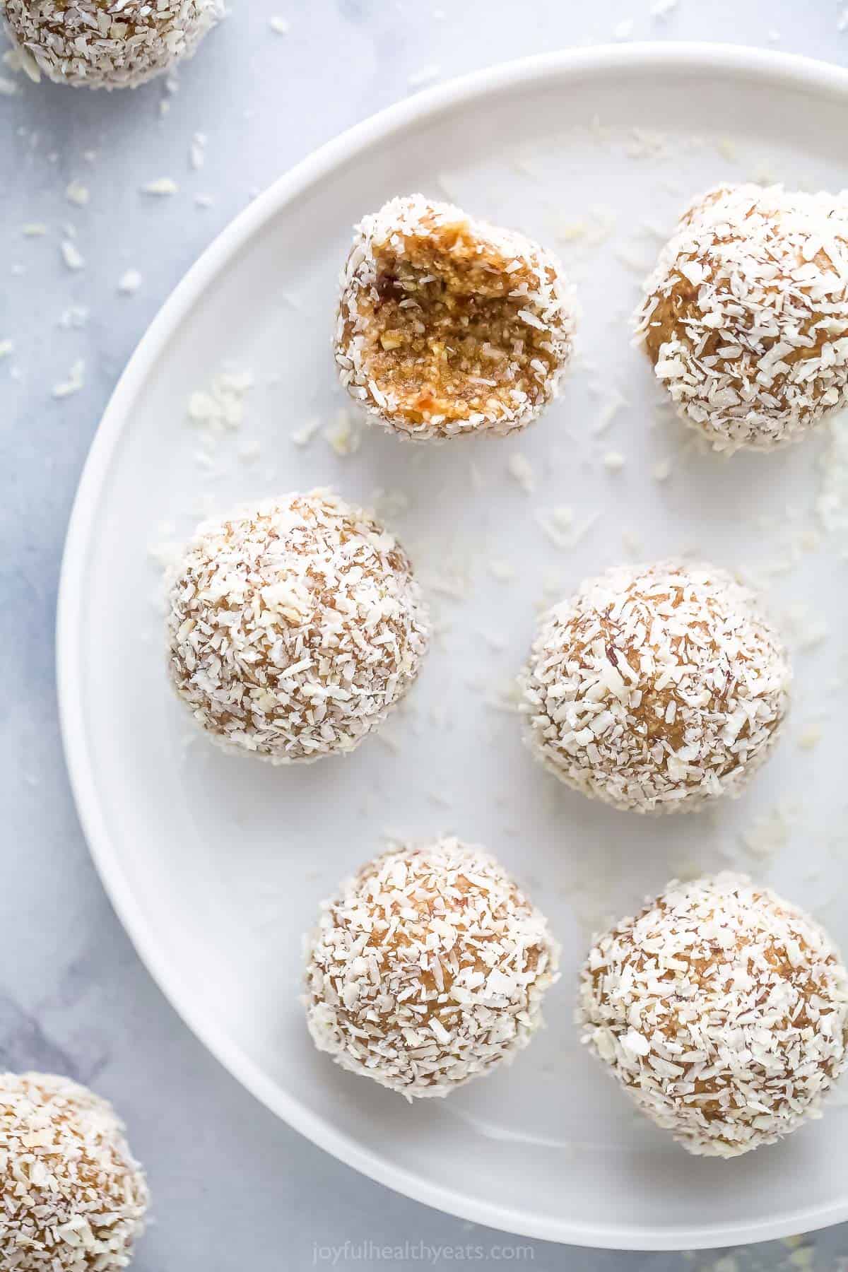 Coconut protein bites on a white plate with a raised rim