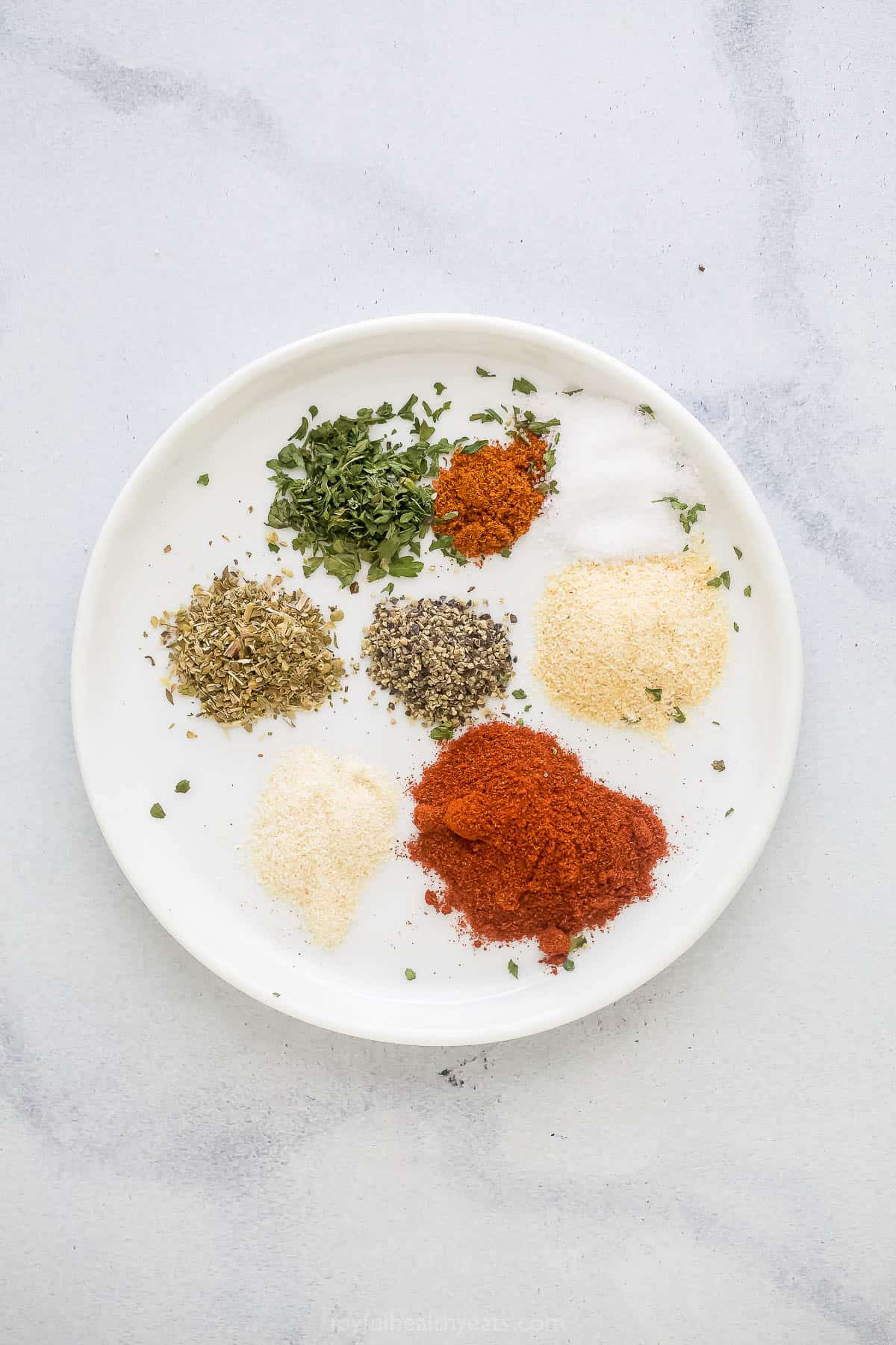 A plate on a marble countertop holding all of the blackening spice ingredients