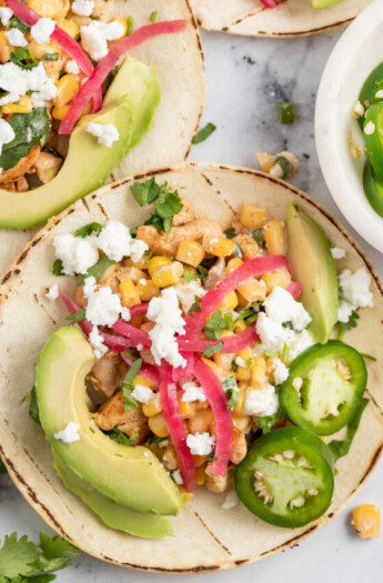 Chicken Street Tacos with pickled onions, Mexican Street Corn salad, and sliced avocados