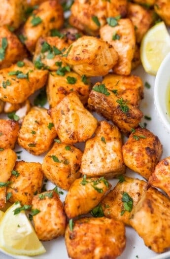 Close-up of air fryer salmon bites with a lemon wedge on the side.