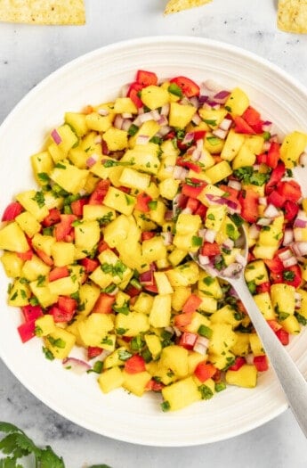 Bowl of pineapple salsa with a metal spoon.