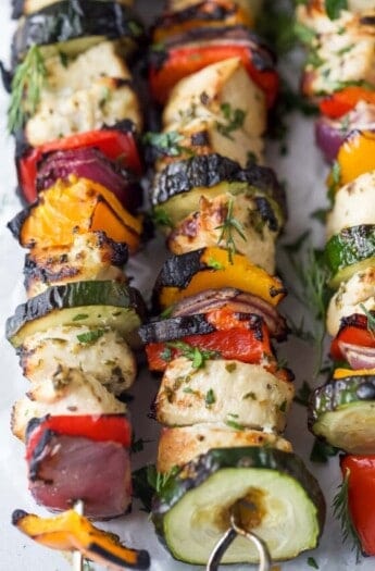 Close-up of charred veggies and chicken on the Mediterranean chicken kabobs.