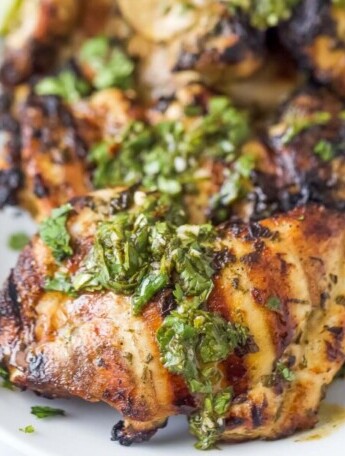 Close-up of grilled chicken with chimichurri on top.