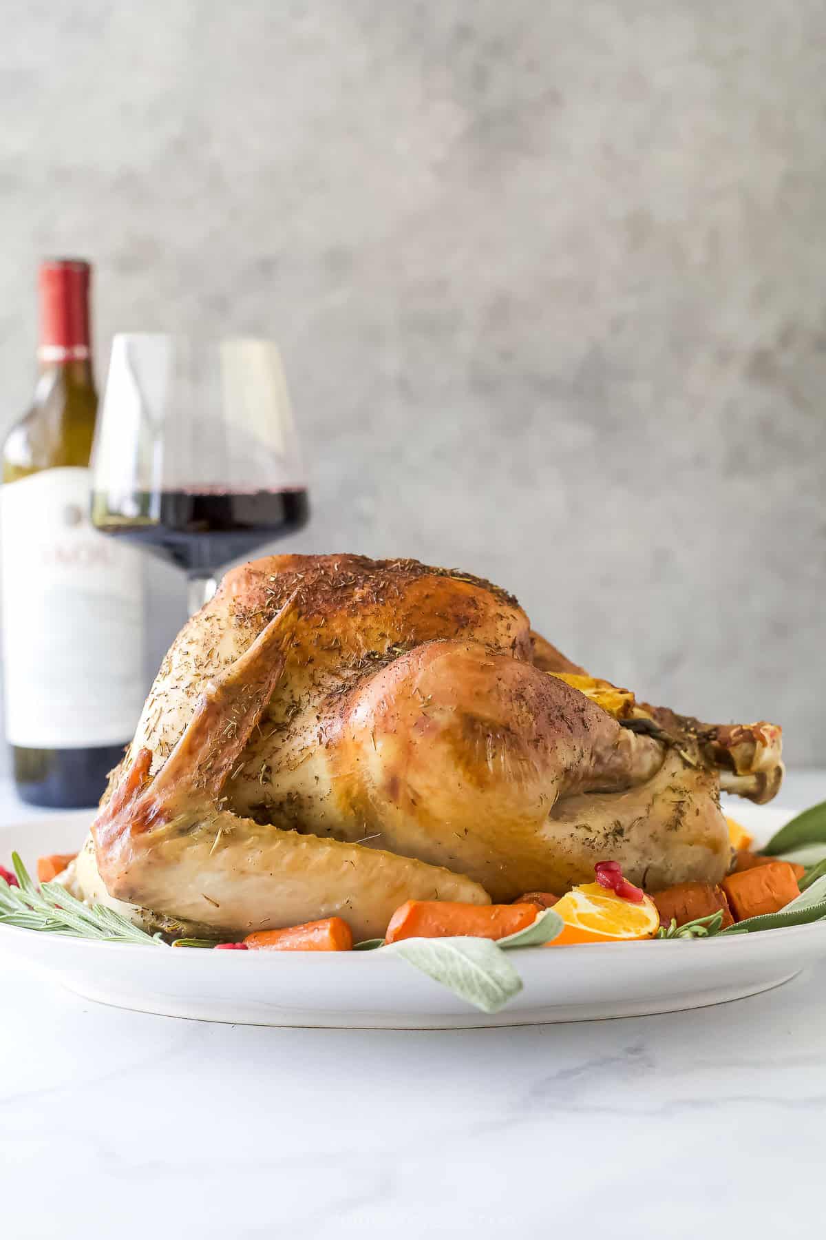 Roast whole turkey with crispy skin on a serving platter with a glass of wine in the background.